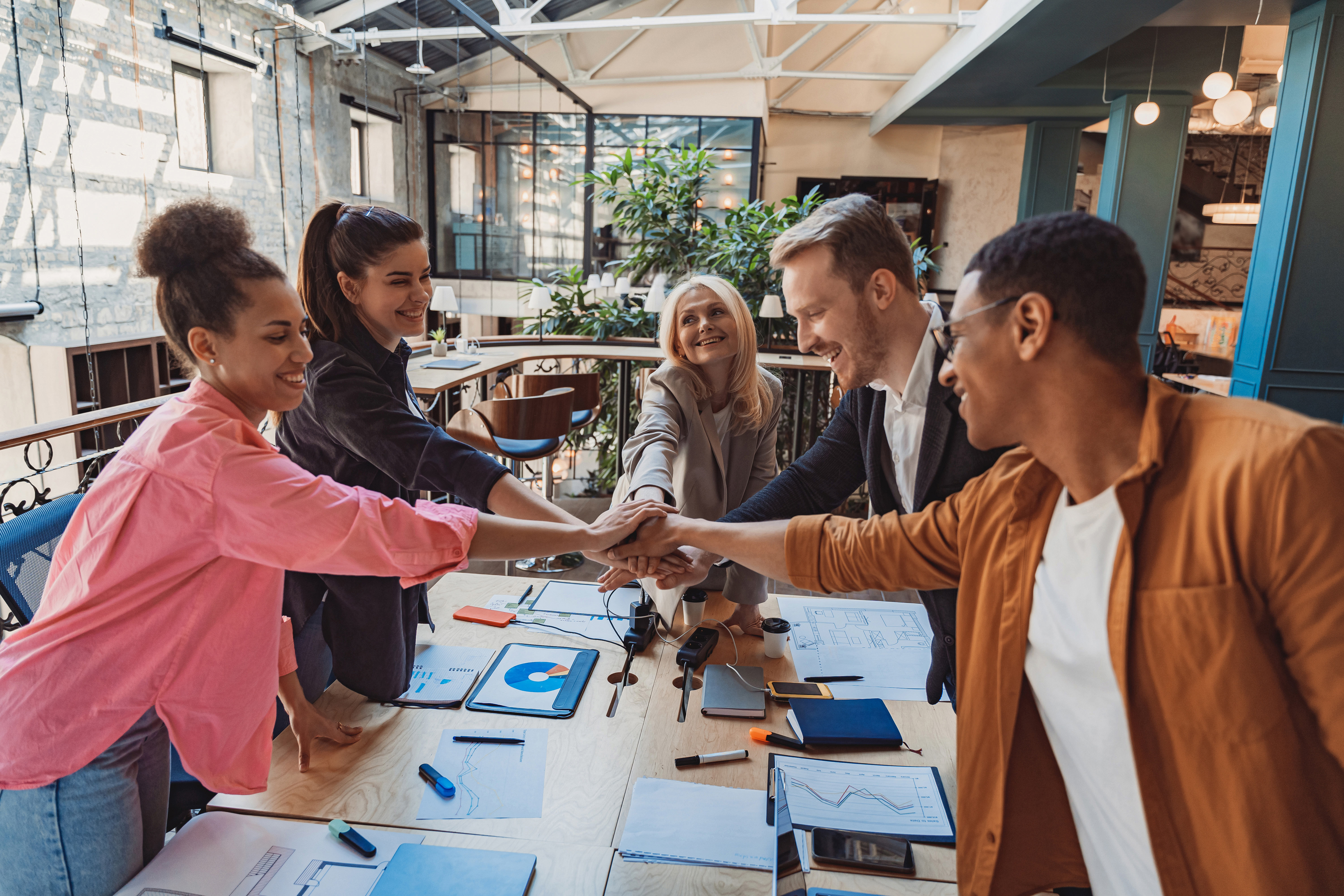 A group of young professionals holding hands with each other in an office
